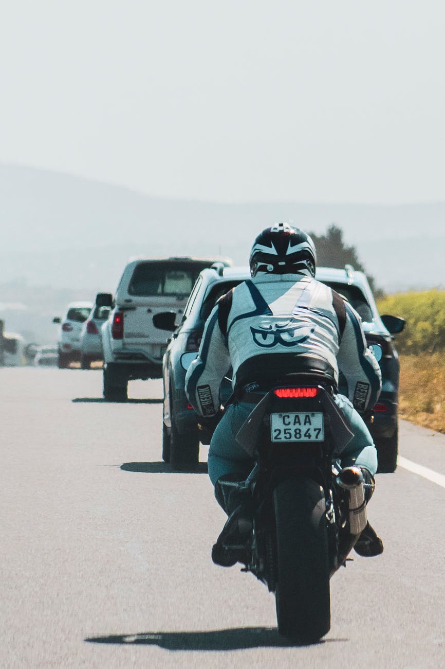 unrecognizable biker driving motorcycle on road